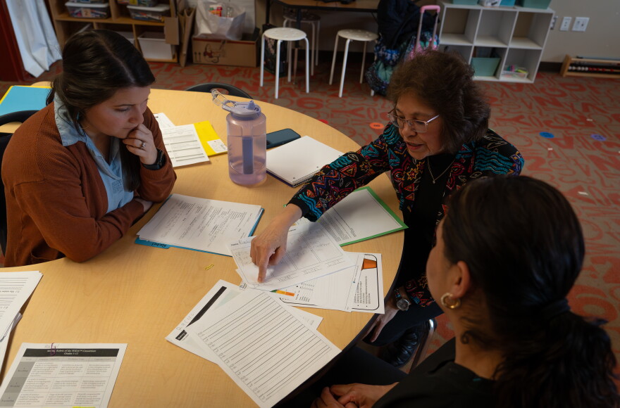 A woman discusses something on a paper with two other women.