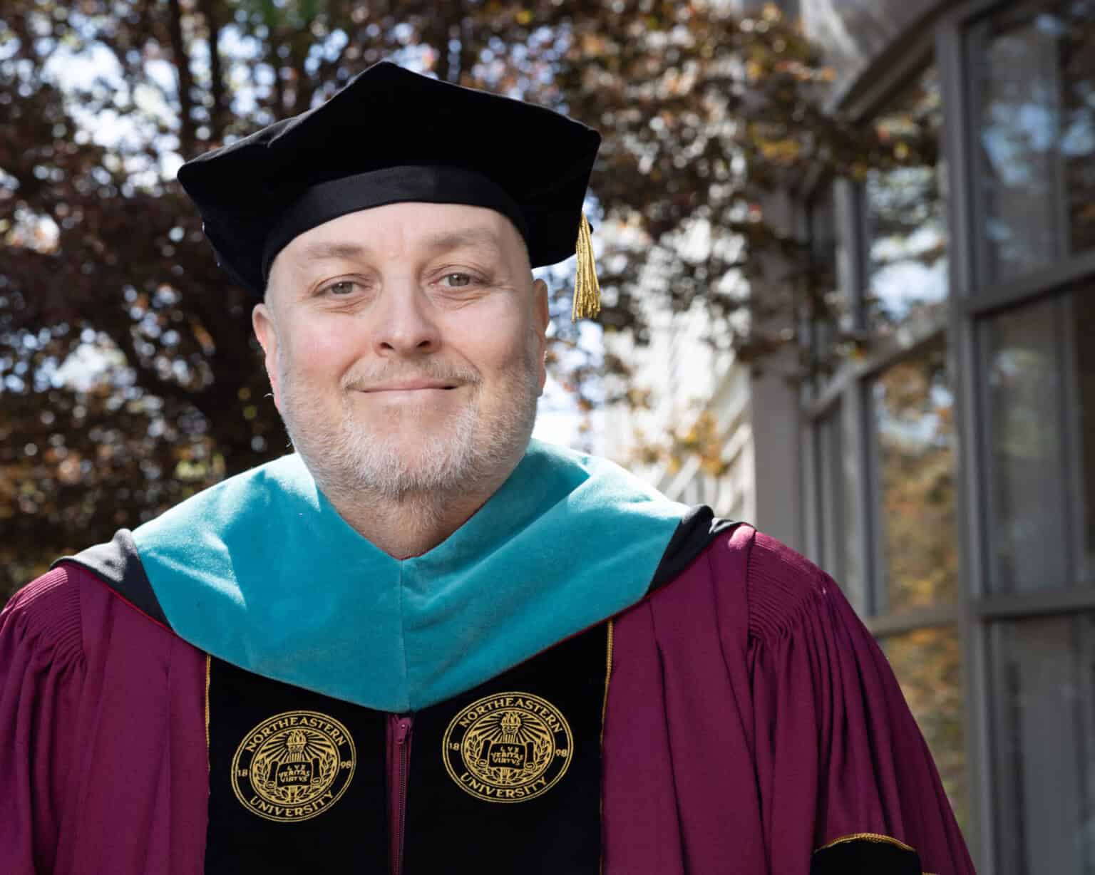 Academic graduate wearing cap and gown celebrating diversity in education outdoors.