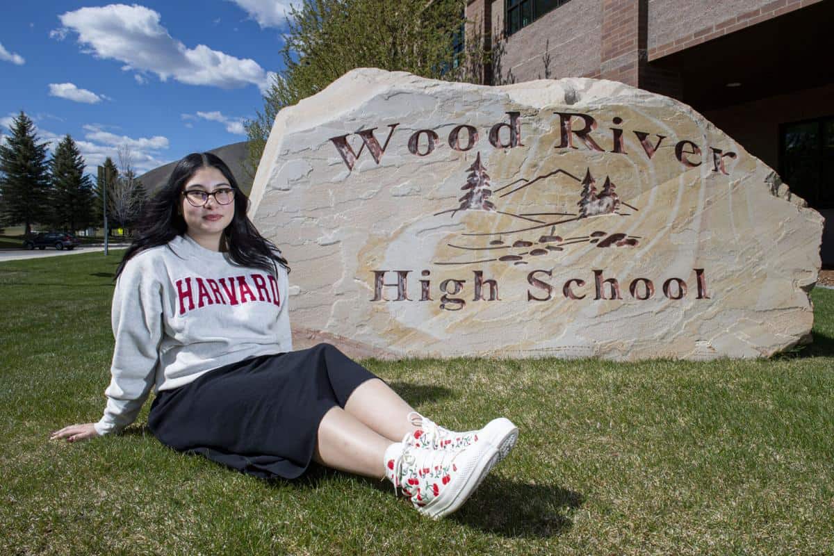 Hispanic student from Wood River High School sitting by the school sign.