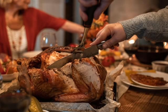 Traditional Thanksgiving turkey being carved at a family dinner.