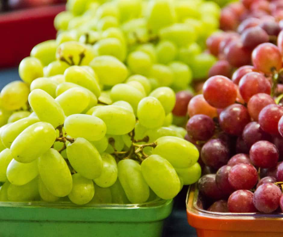 Green and red grapes displayed at a market stall, highlighting traditional fruits used in Latino New.