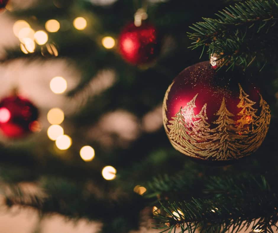 Christmas ornament on a decorated Christmas tree with festive lights in the background.