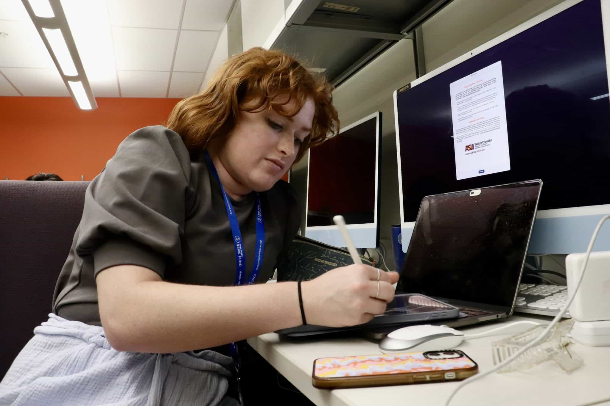 A woman working at a desk with multiple computer monitors, related to Latino News Network and NPR Mi.