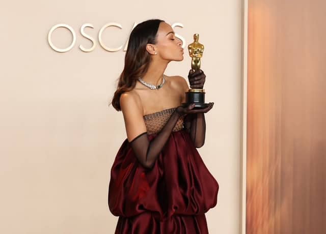 Latina actress Saldaña at Oscars holding her award, celebrating her historic achievement.