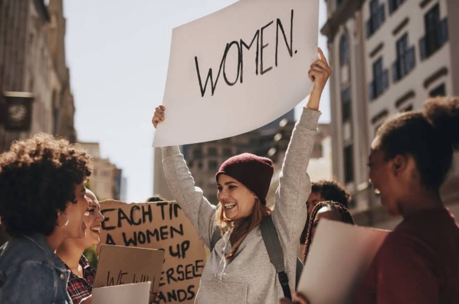 Empowering women rally with diverse women holding signs for gender equality and feminism.