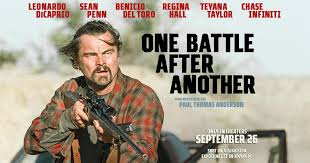 Latino man holding a rifle with a serious expression, outdoors, from "One Battle After Another" film.