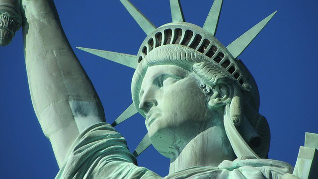 Close-up of the Statue of Liberty's face and crown against a blue sky.