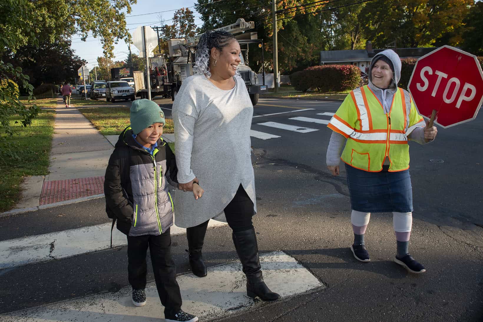 Child and adult crossing guard assisting children at a crosswalk.