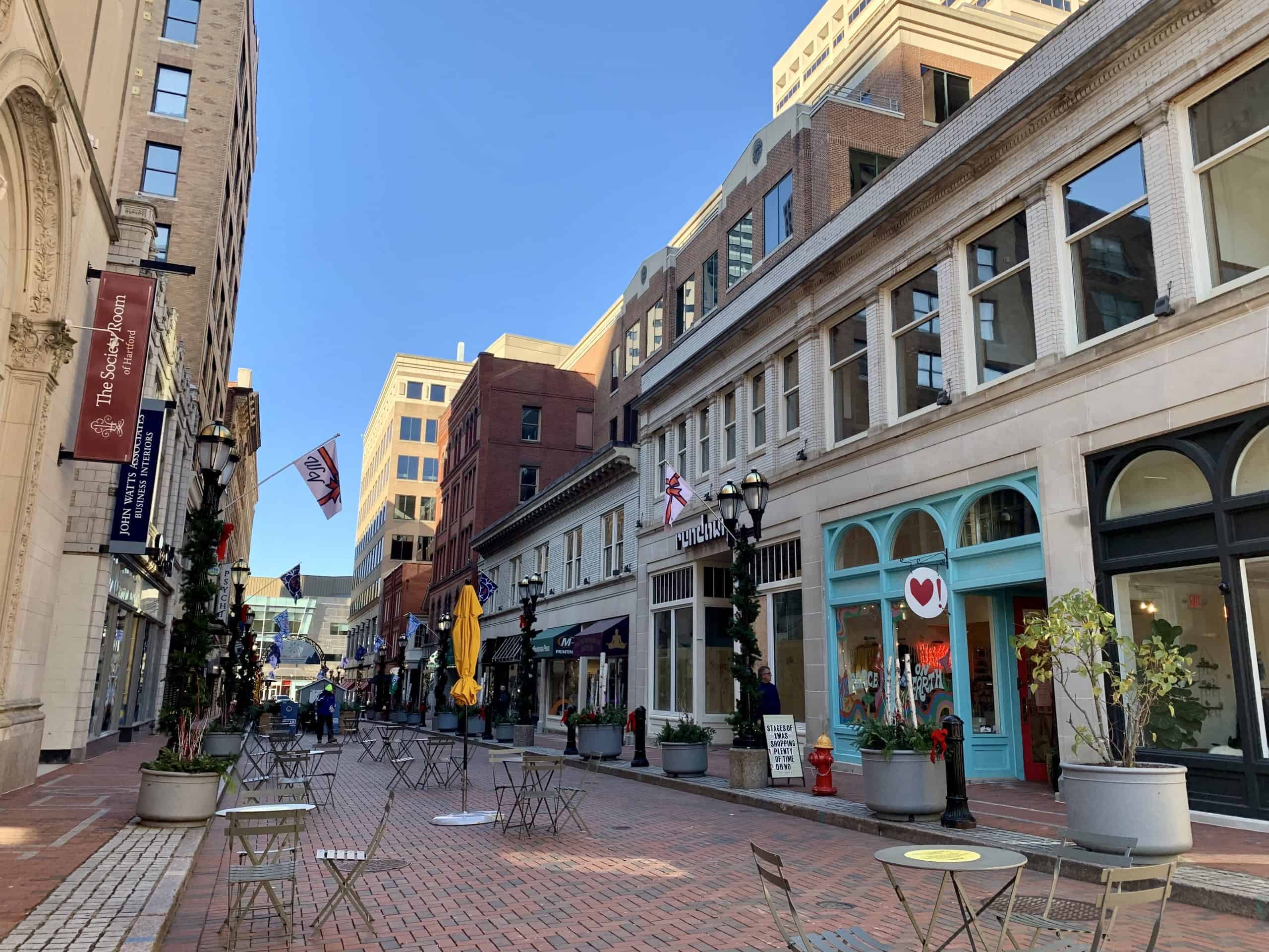 Downtown city street with outdoor cafes and historic buildings, sunny day.
