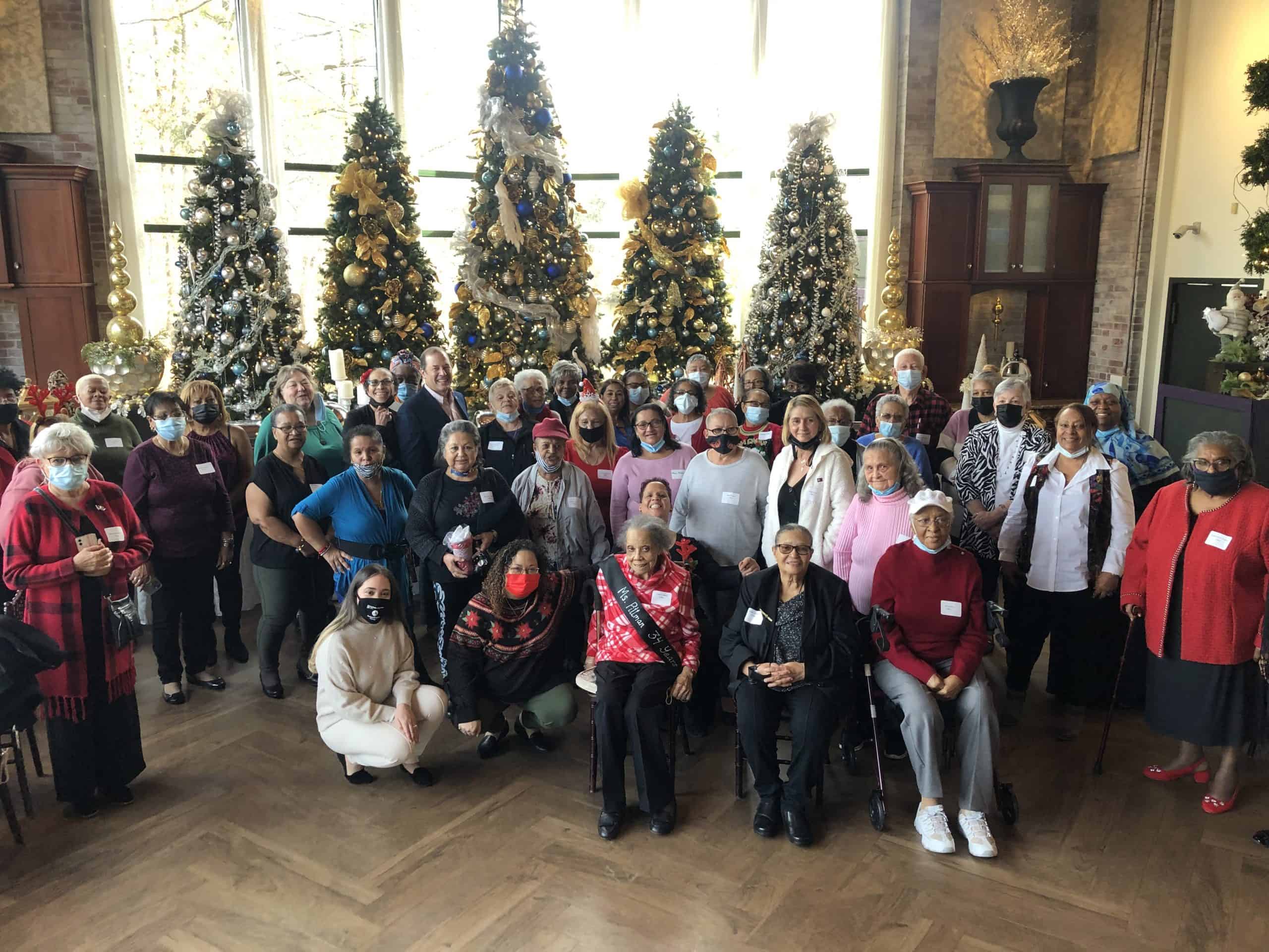 Celebration with diverse children and elderly at community holiday event in front of decorated Chris.