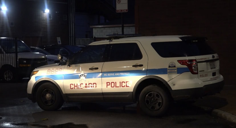 Police car with Chicago Police Department markings on a city street at night.
