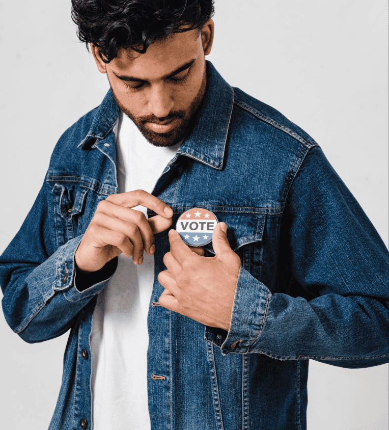 Vote button pin on man's denim jacket, promoting civic engagement and voting.