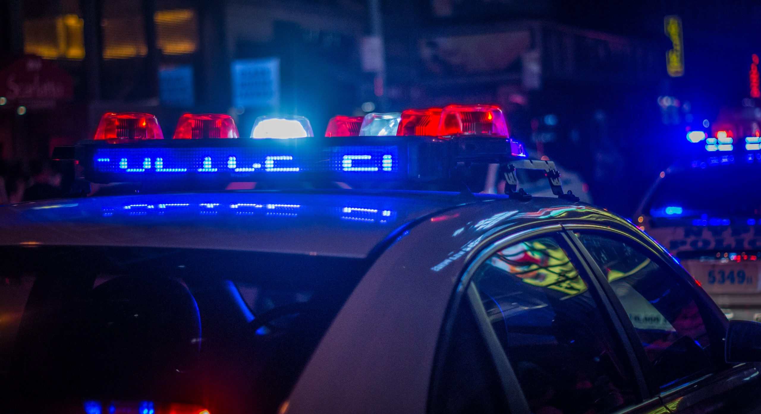 Police car with flashing lights at night, emphasizing law enforcement presence.