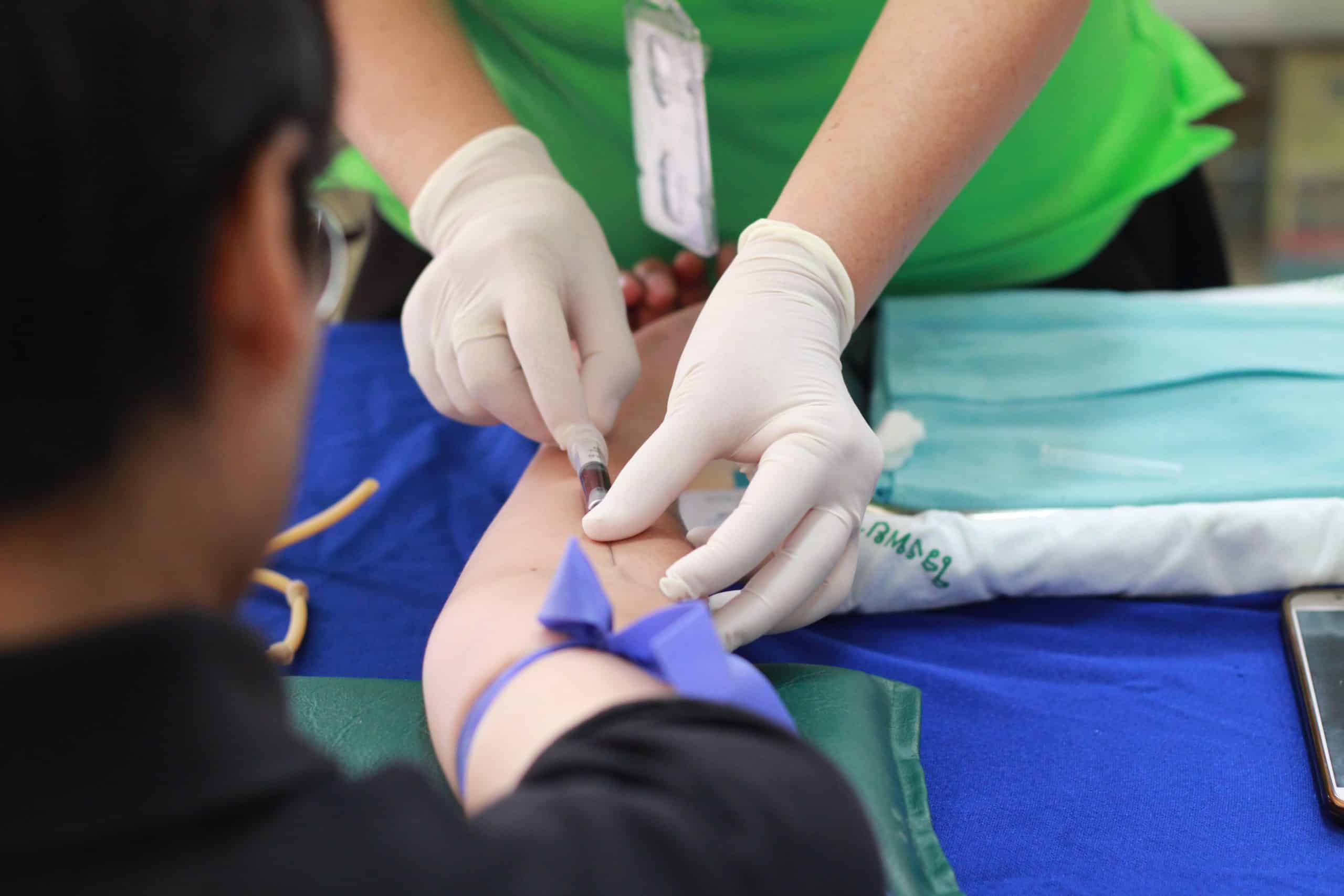 Blood donation process with healthcare professional preparing to draw blood from a donor.