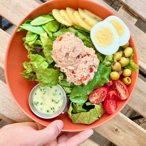 Delicious salad with boiled eggs, tomatoes, olives, and tuna salad.