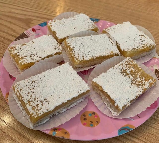 Cream-filled pastries dusted with powdered sugar on a pink plate.