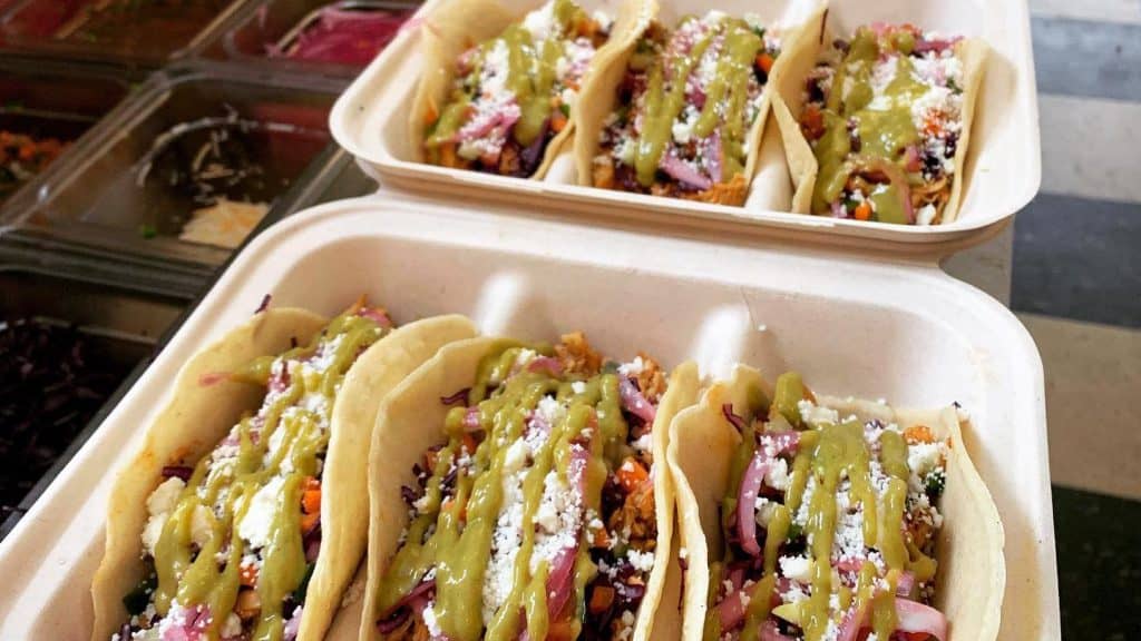 Freshly prepared tacos with vibrant toppings and green sauce at Lalo’s Taqueria in New Hampshire.
