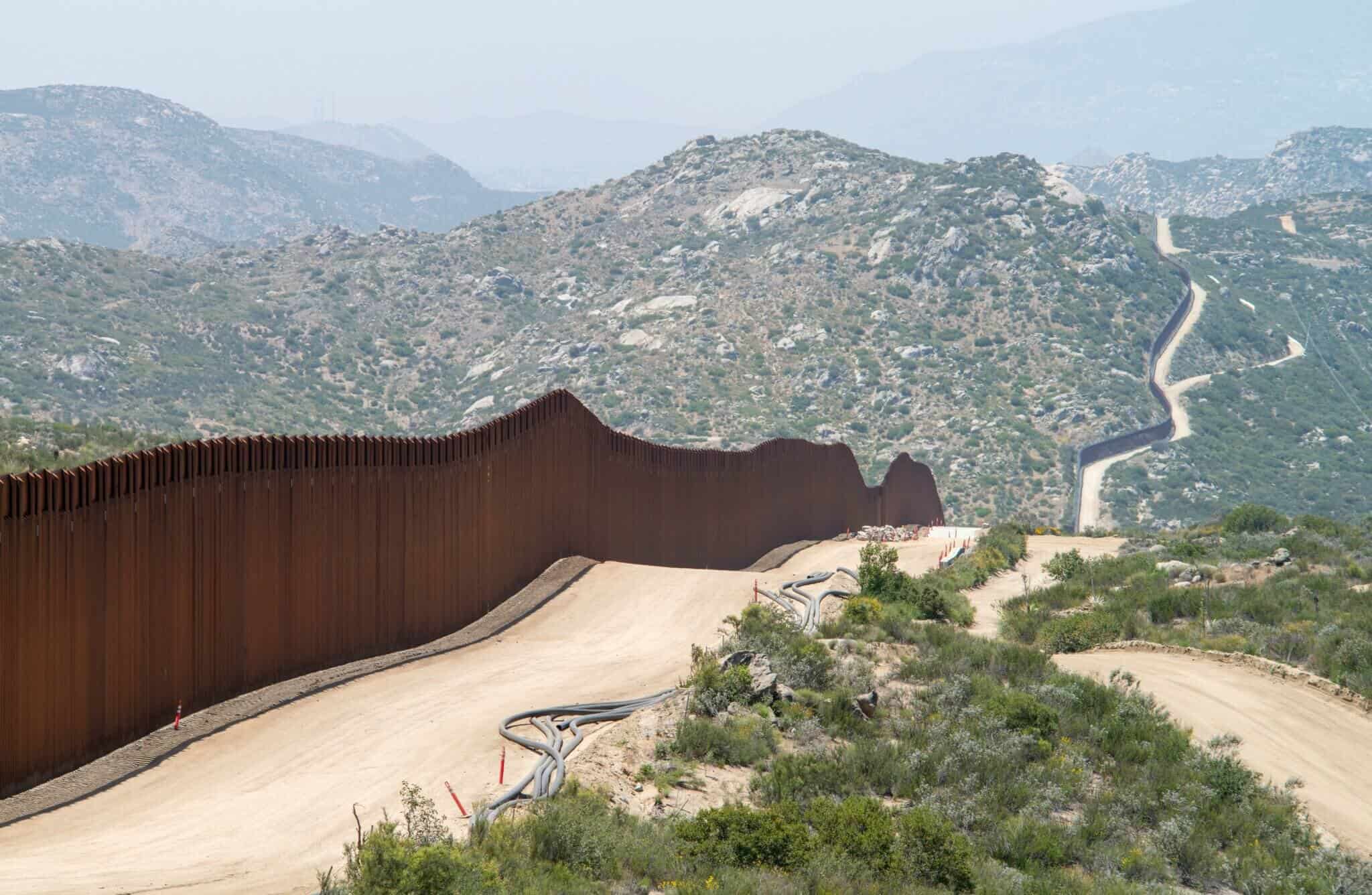 Border wall construction along the southern border with mountains in the background.