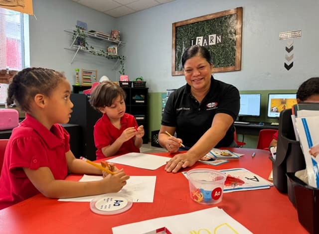 Early childhood educator engaging with young students in a classroom setting.
