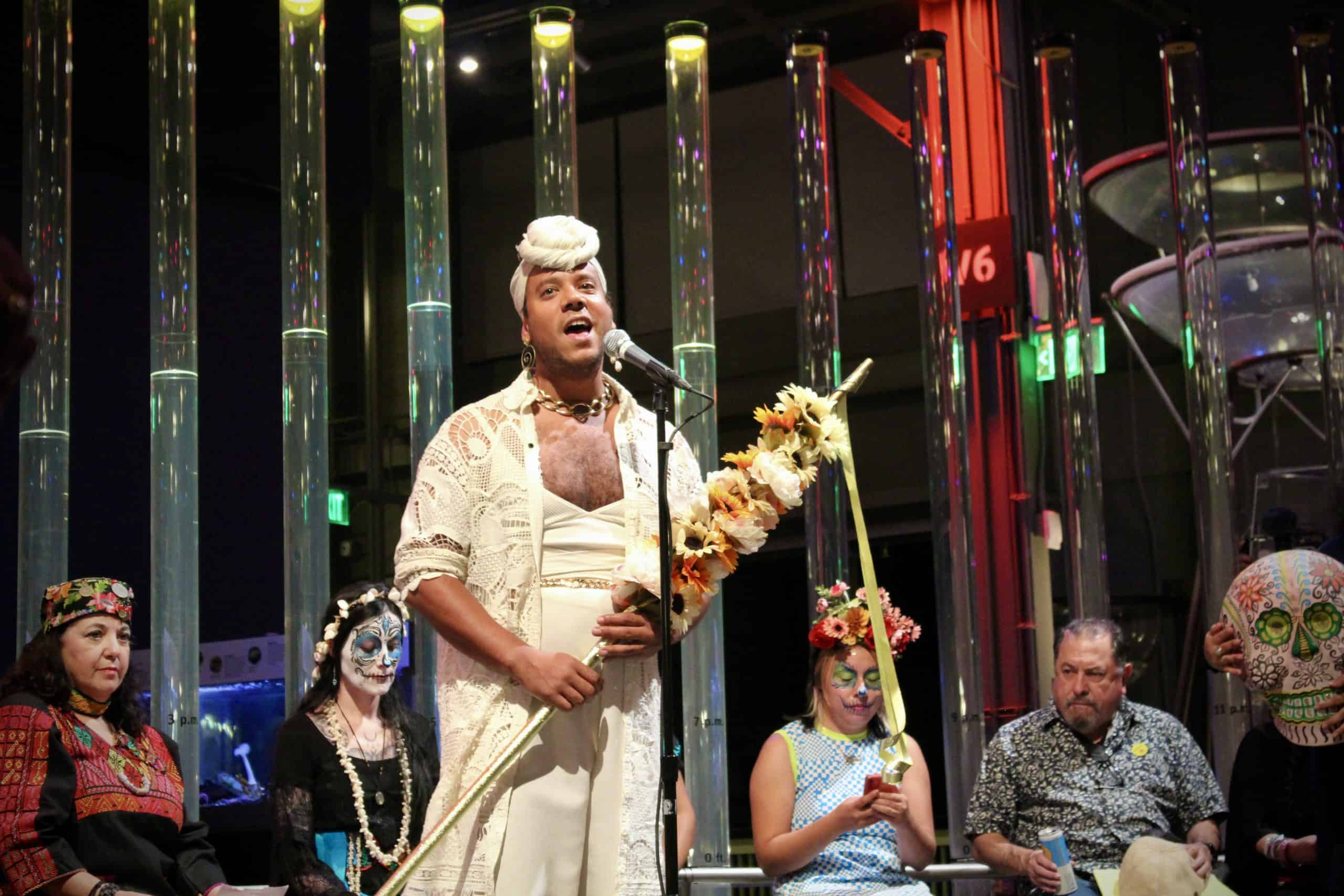 Performer singing at a cultural event with traditional costumes and face paint.