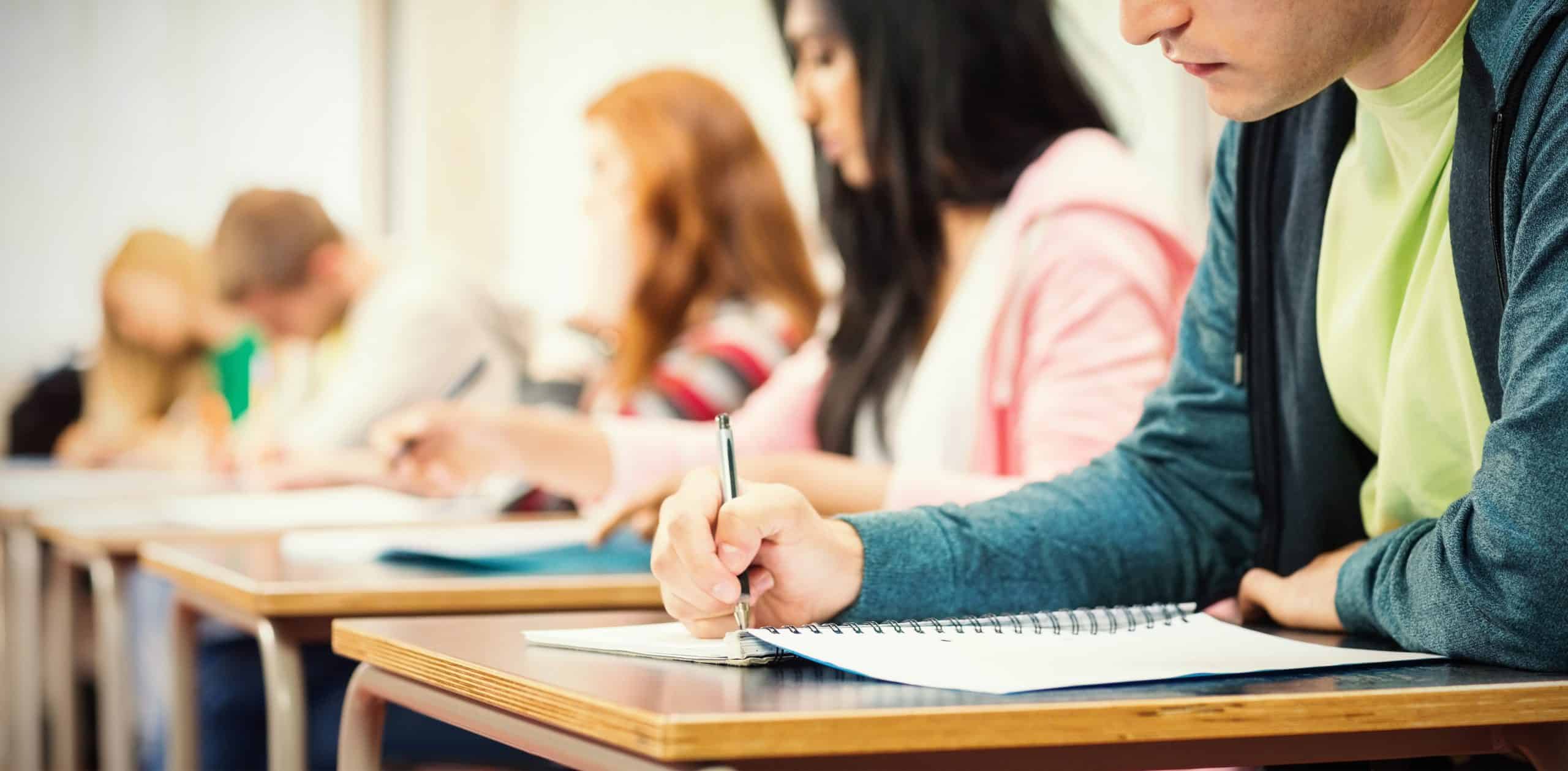 Students taking notes in a classroom to address education challenges in New York.