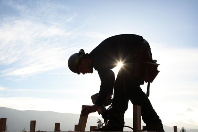 Construction worker working outdoors during sunset with safety gear.