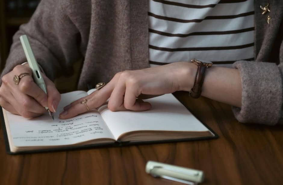 A woman writing in a notebook, highlighting the need for academic reform to support women of color.