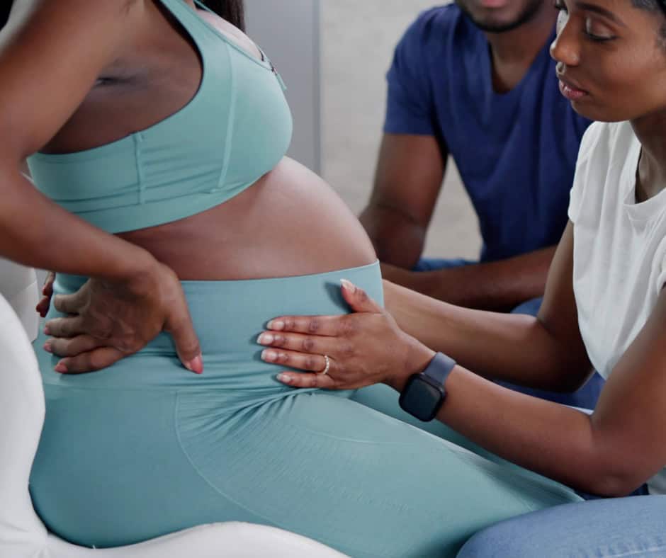 Pregnant woman receiving emotional support from a community doula during childbirth preparation.