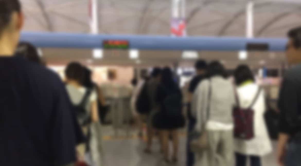 A crowded airport terminal with diverse travelers waiting in line.