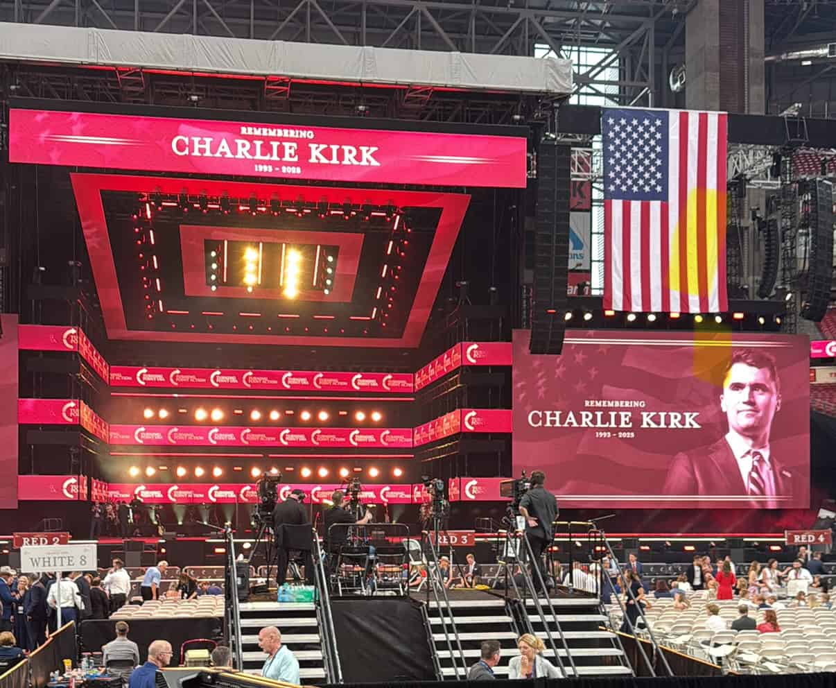 Charlie Kirk memorial stage at a political event with American flag backdrop.