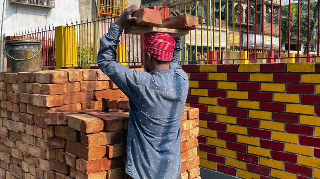 A man carrying bricks on his head at a construction site.