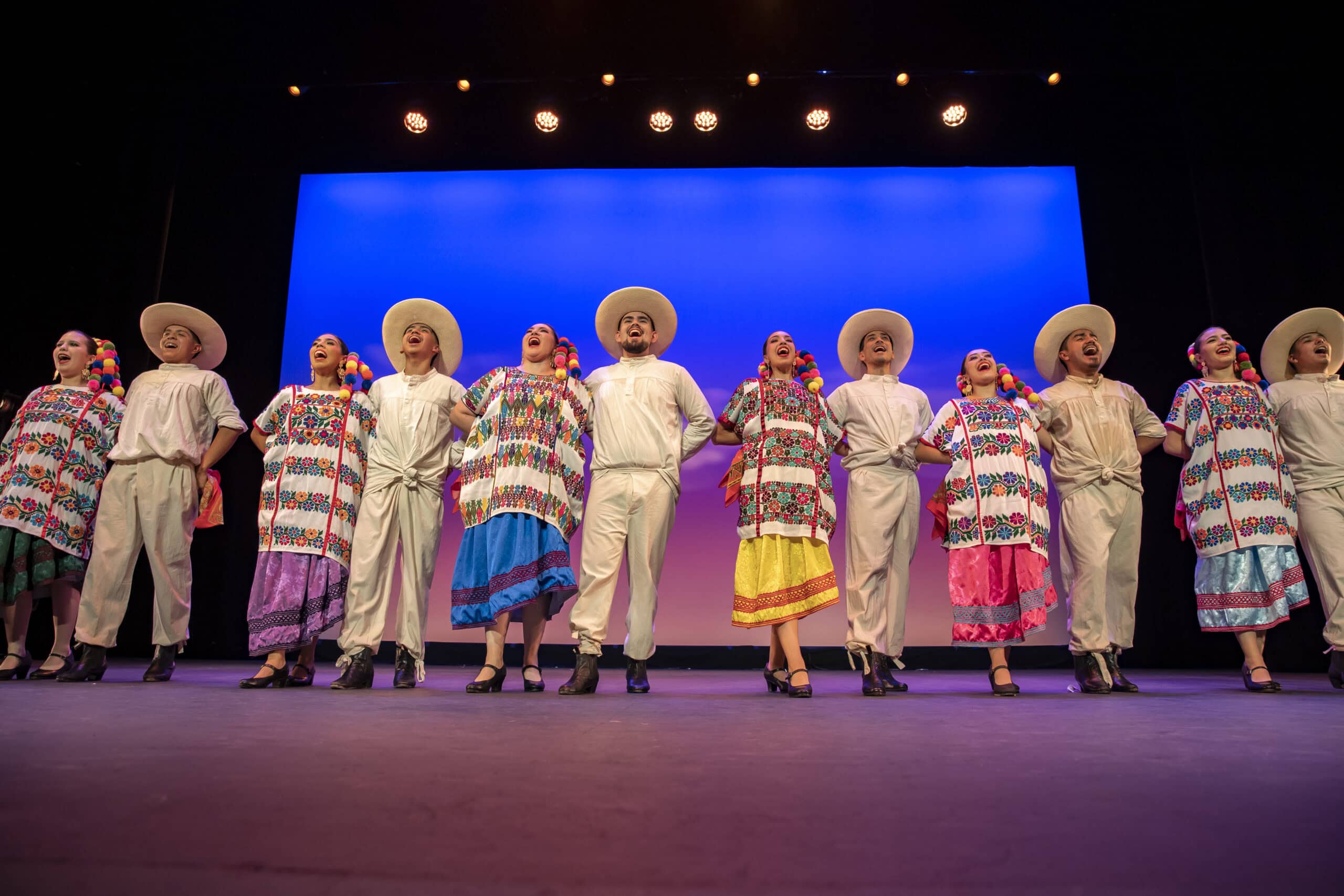 A colorful group of dancers performing traditional Latin American dance on stage.