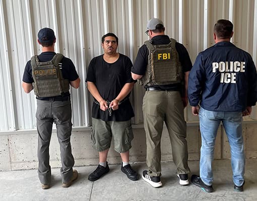 A man in custody with law enforcement officers at detention center.