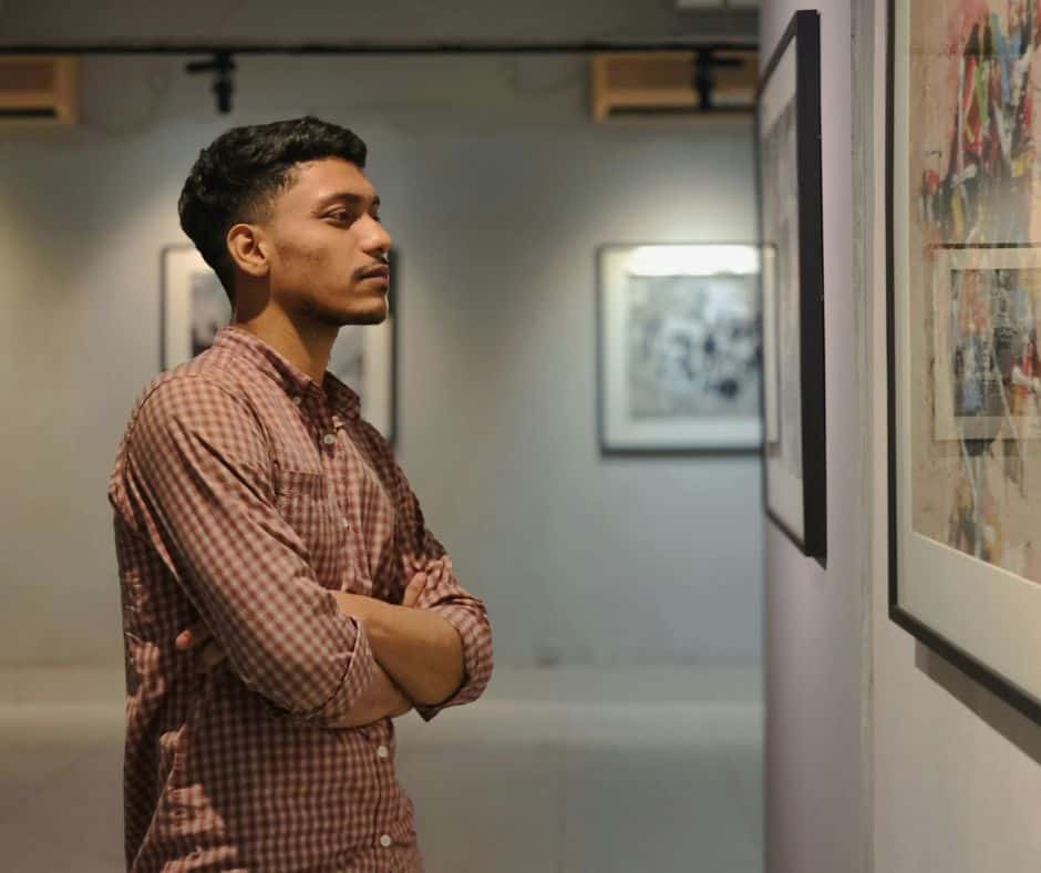 Young man viewing artwork at an art gallery, contemplating the piece.
